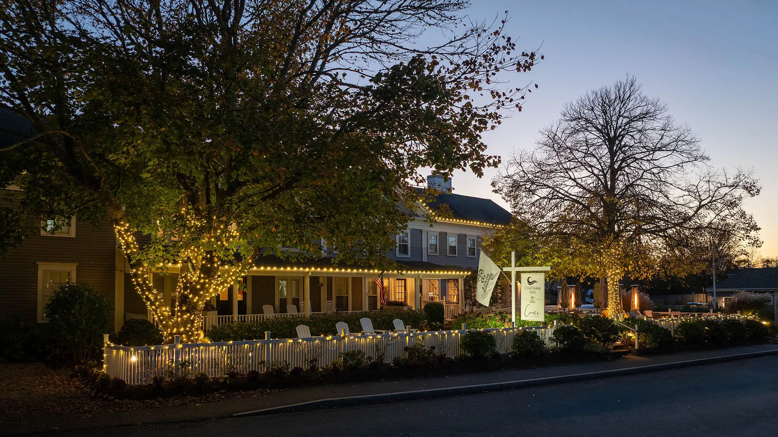Chatham Inn Relais & Châteaux exterior glowing with string lights at dusk on Main Street in Chatham, Cape Cod, Massachusetts.