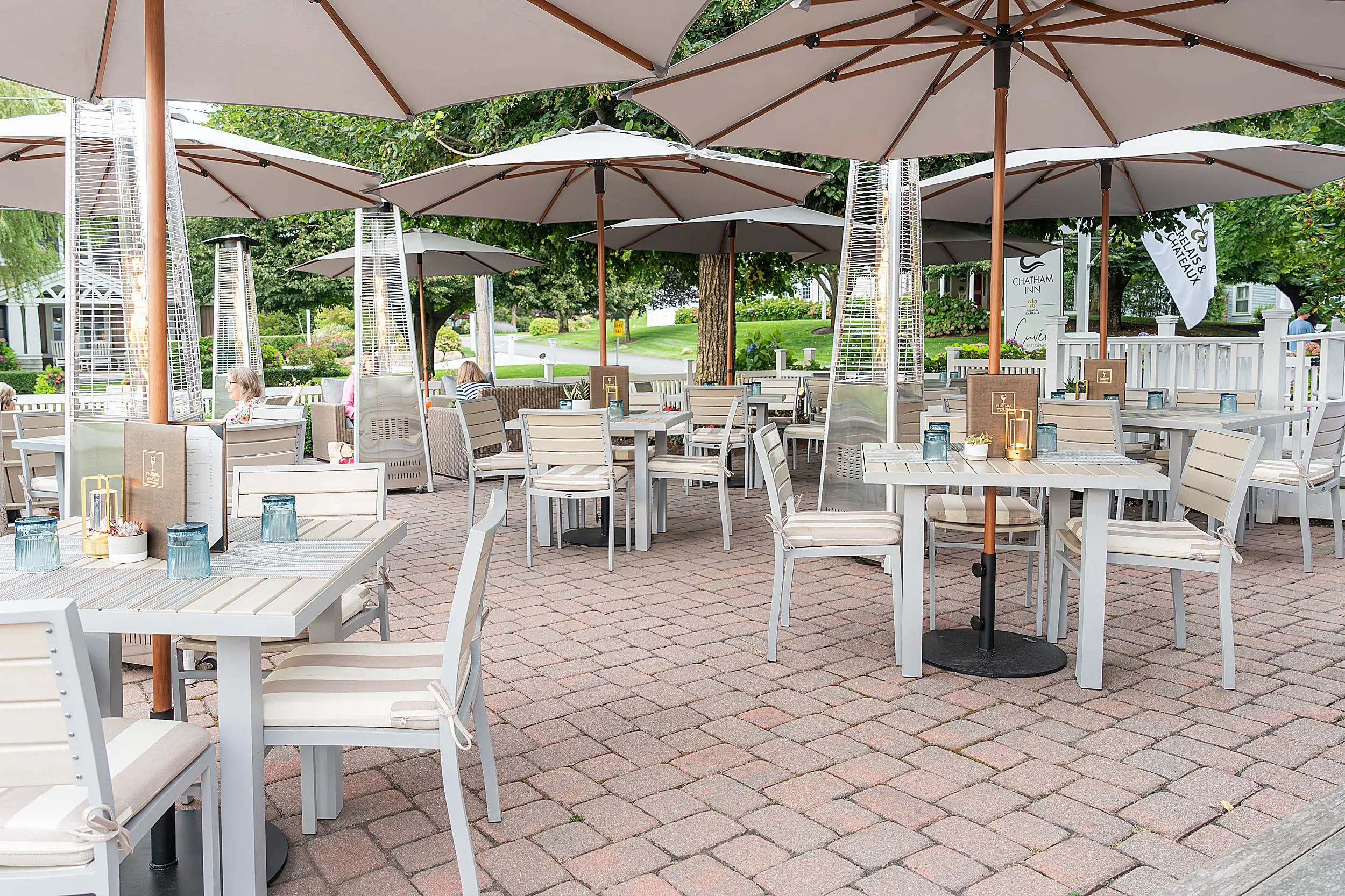 Outdoor seating area with umbrella-shaded tables at Chatham Inn's Cuvée Restaurant.