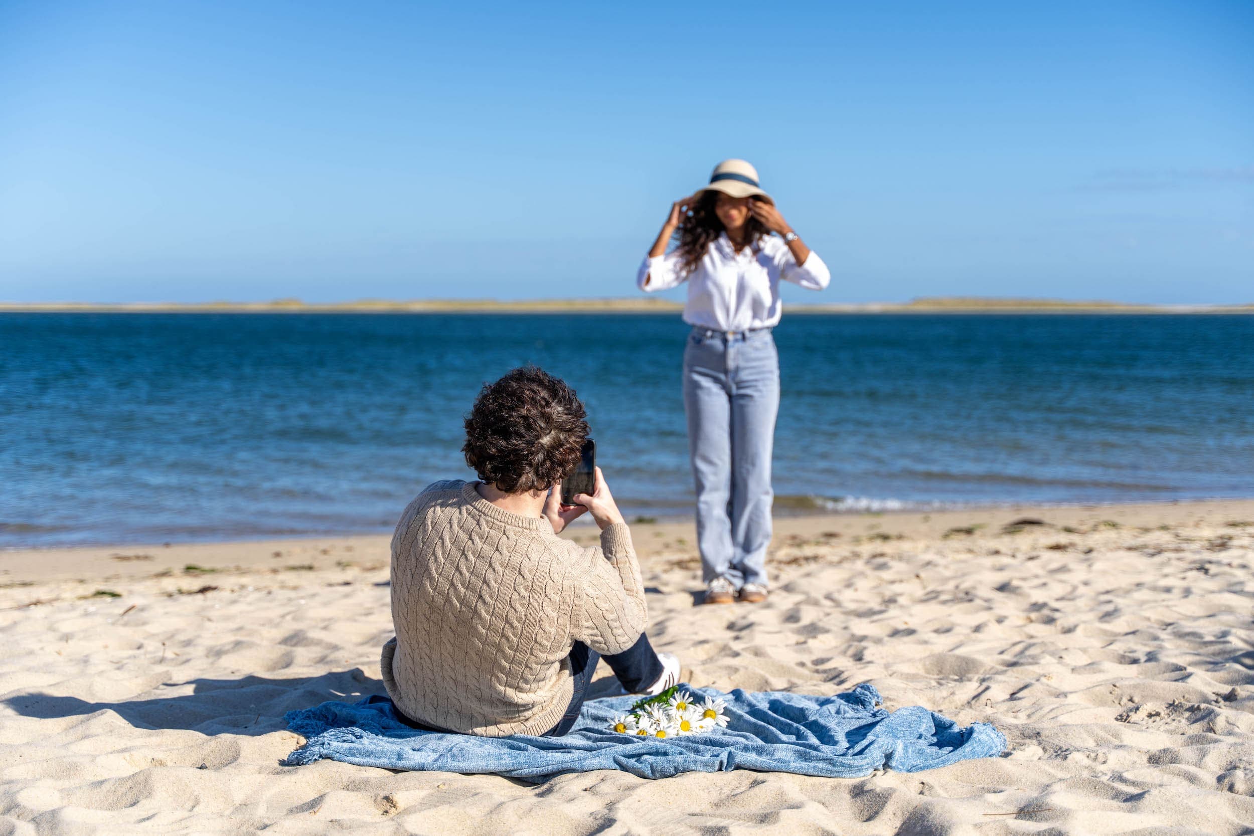 A man taking a picture of a woman on the beach near the Chatham Inn