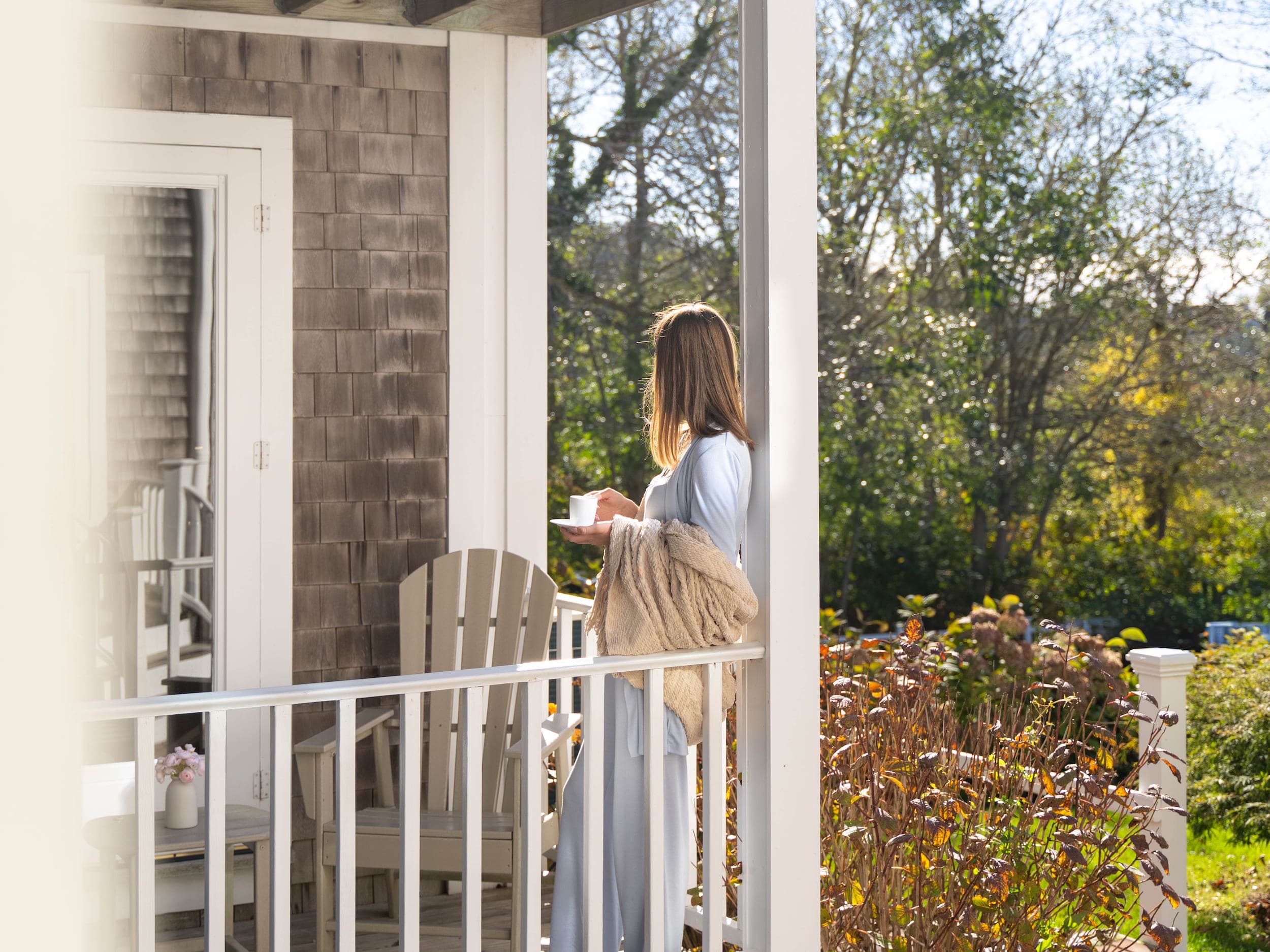 A woman on a patio off of a room at Chatham Inn drinking coffee