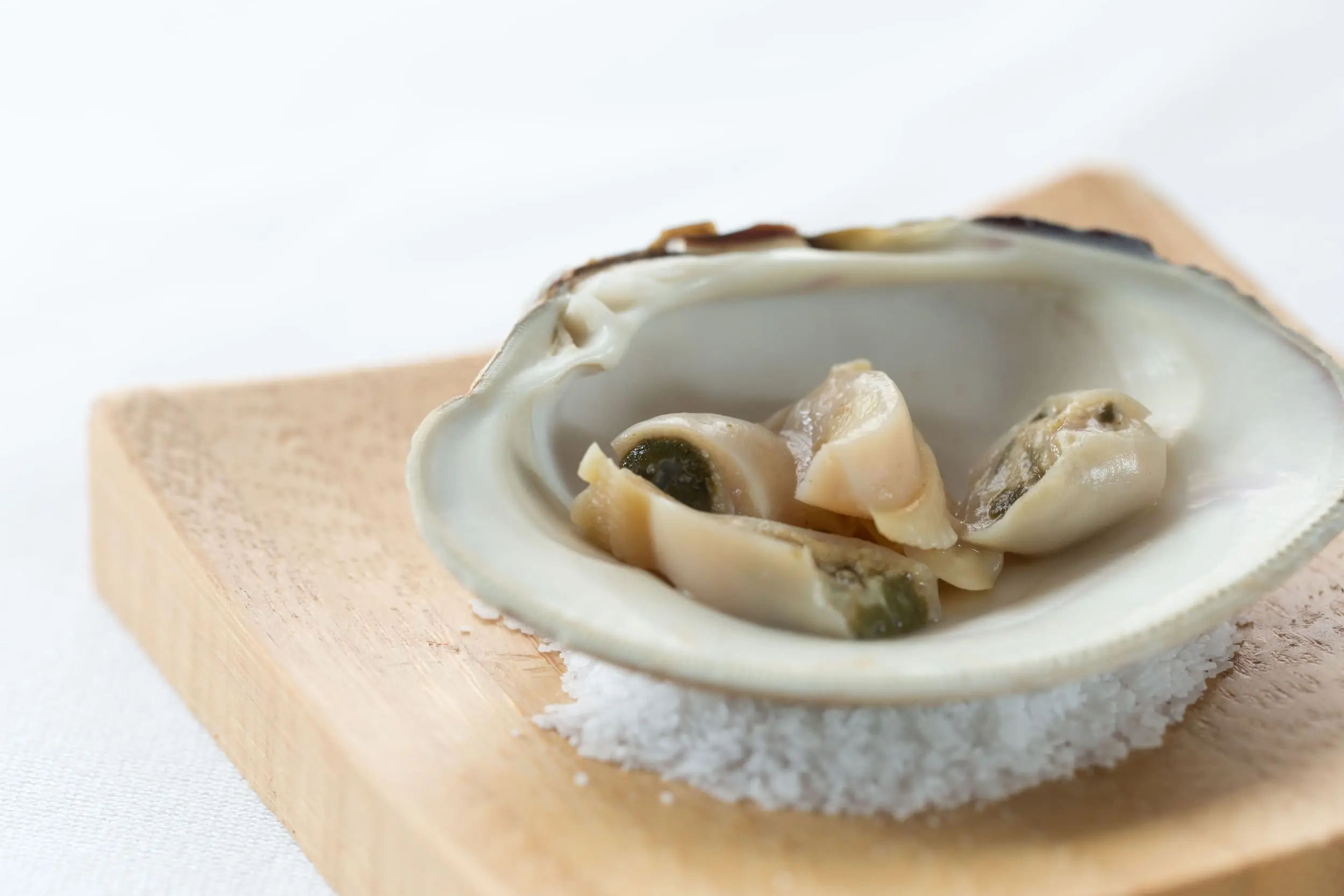 An oyster chopped up in an oyster shell on a bed of sea salt