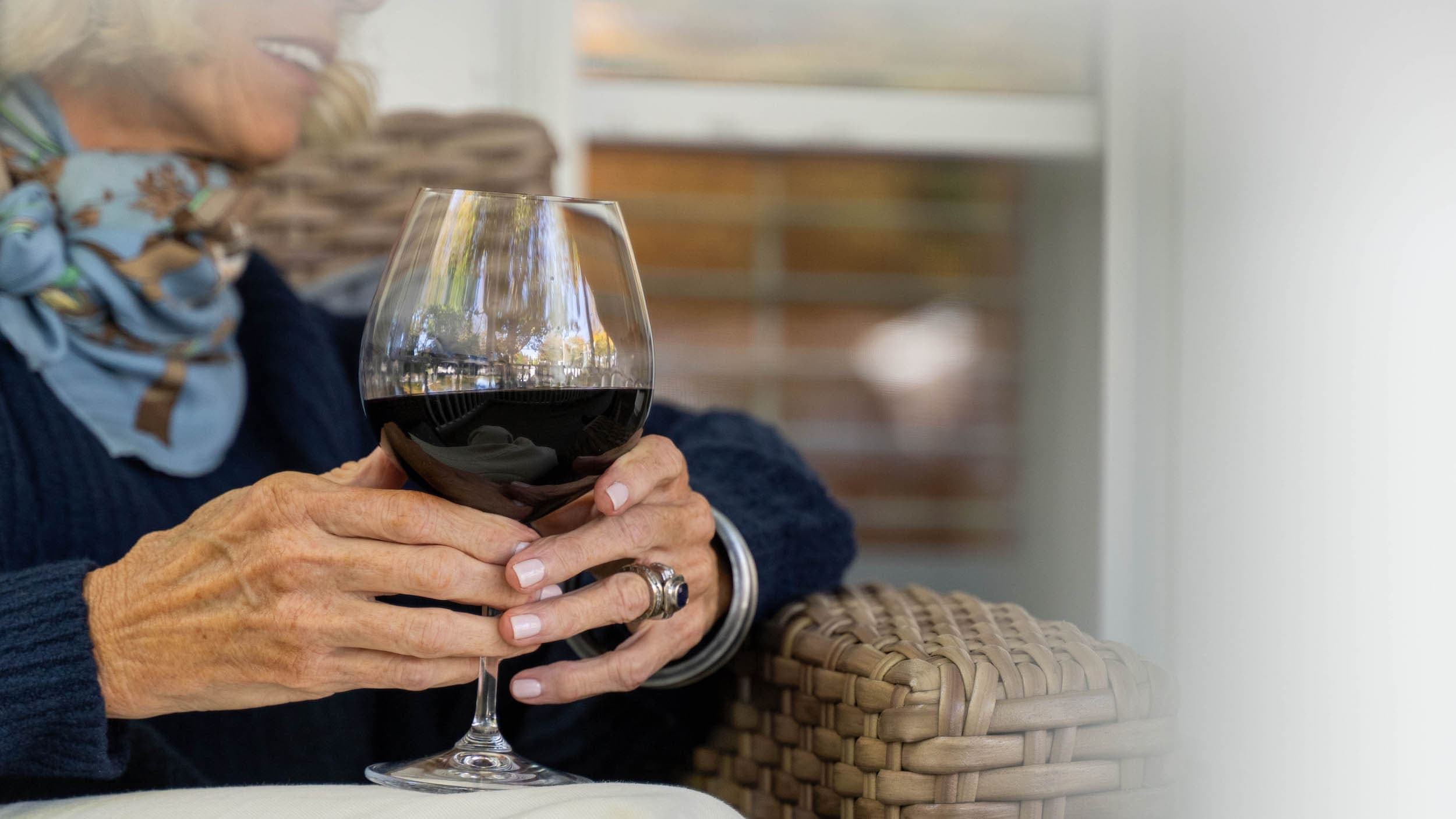 A woman sitting on a balcony at Chatham Inn having a glass of red wine
