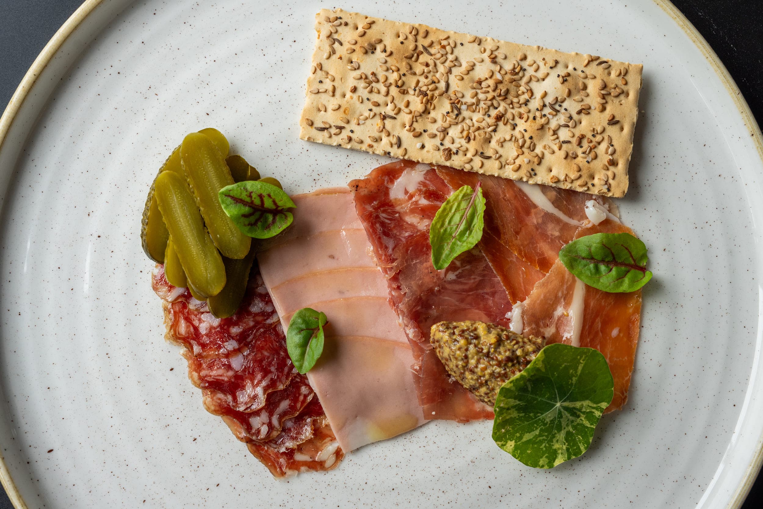 A Charcuterie Plate at Chatham Inn with cured meats, pickles. seedy mustard, and sesame cracker