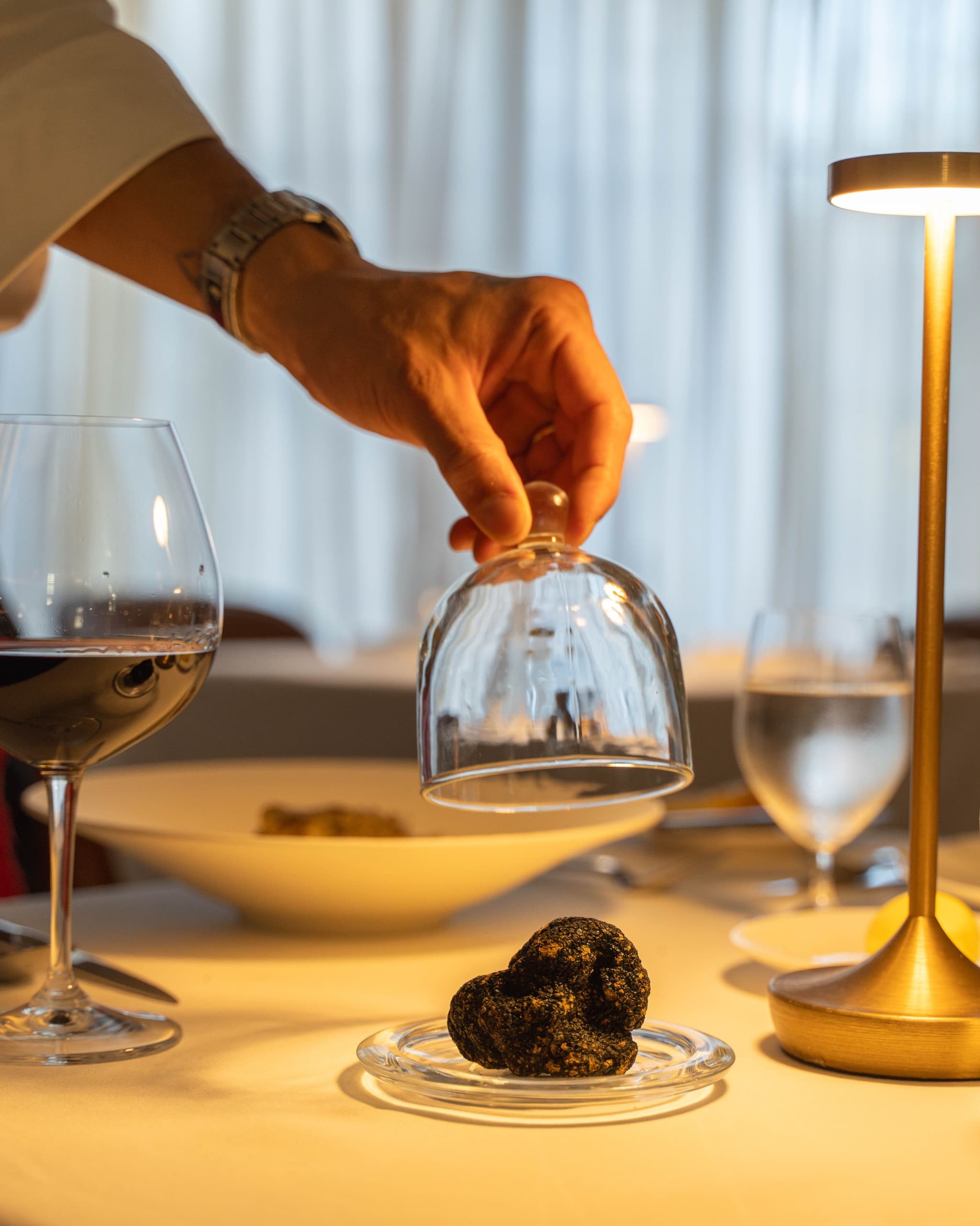 A server taking off a glass cover from a dish holding a truffle at Cuvee Restaurant