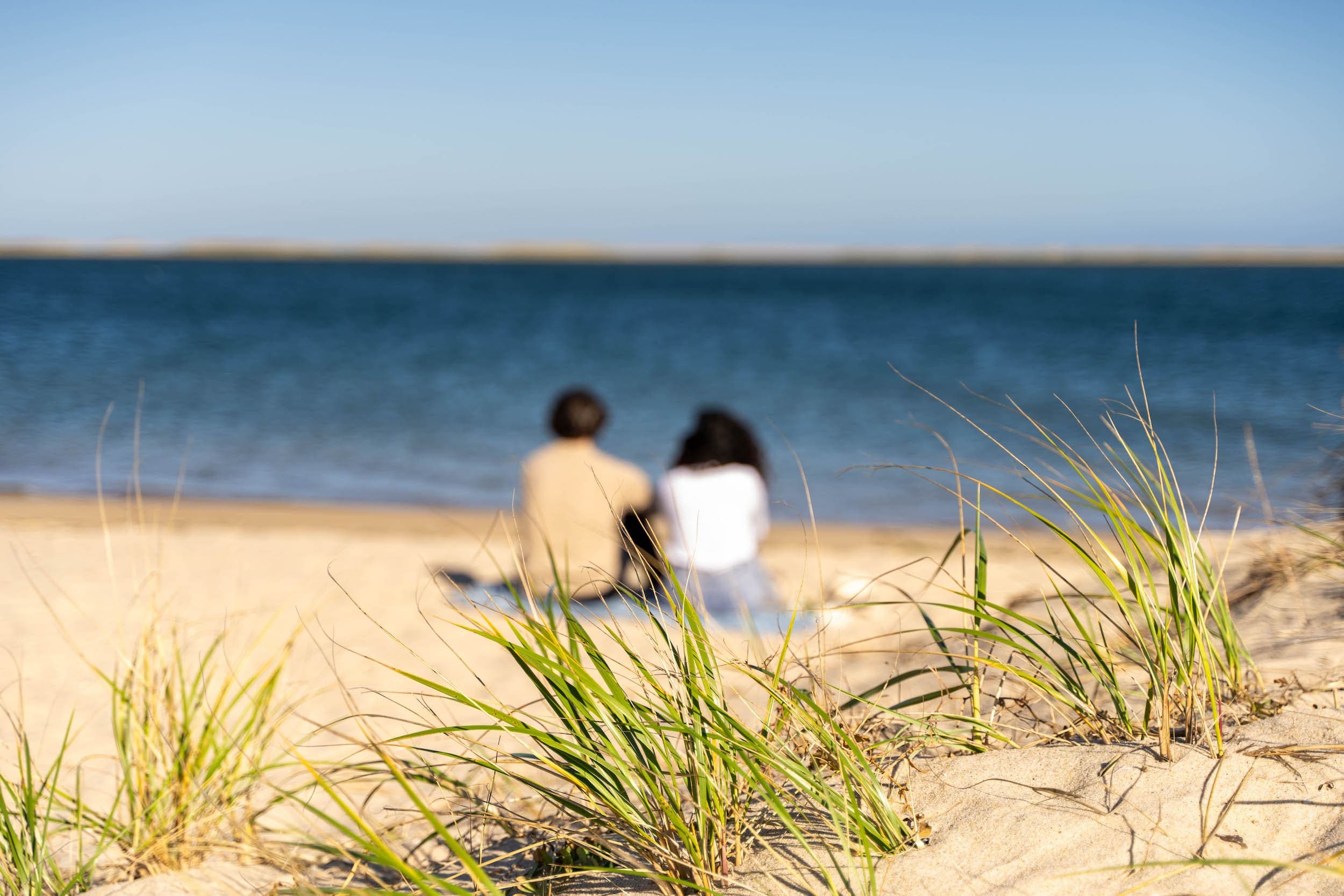 A couple sitting on the beach near Chatham Inn