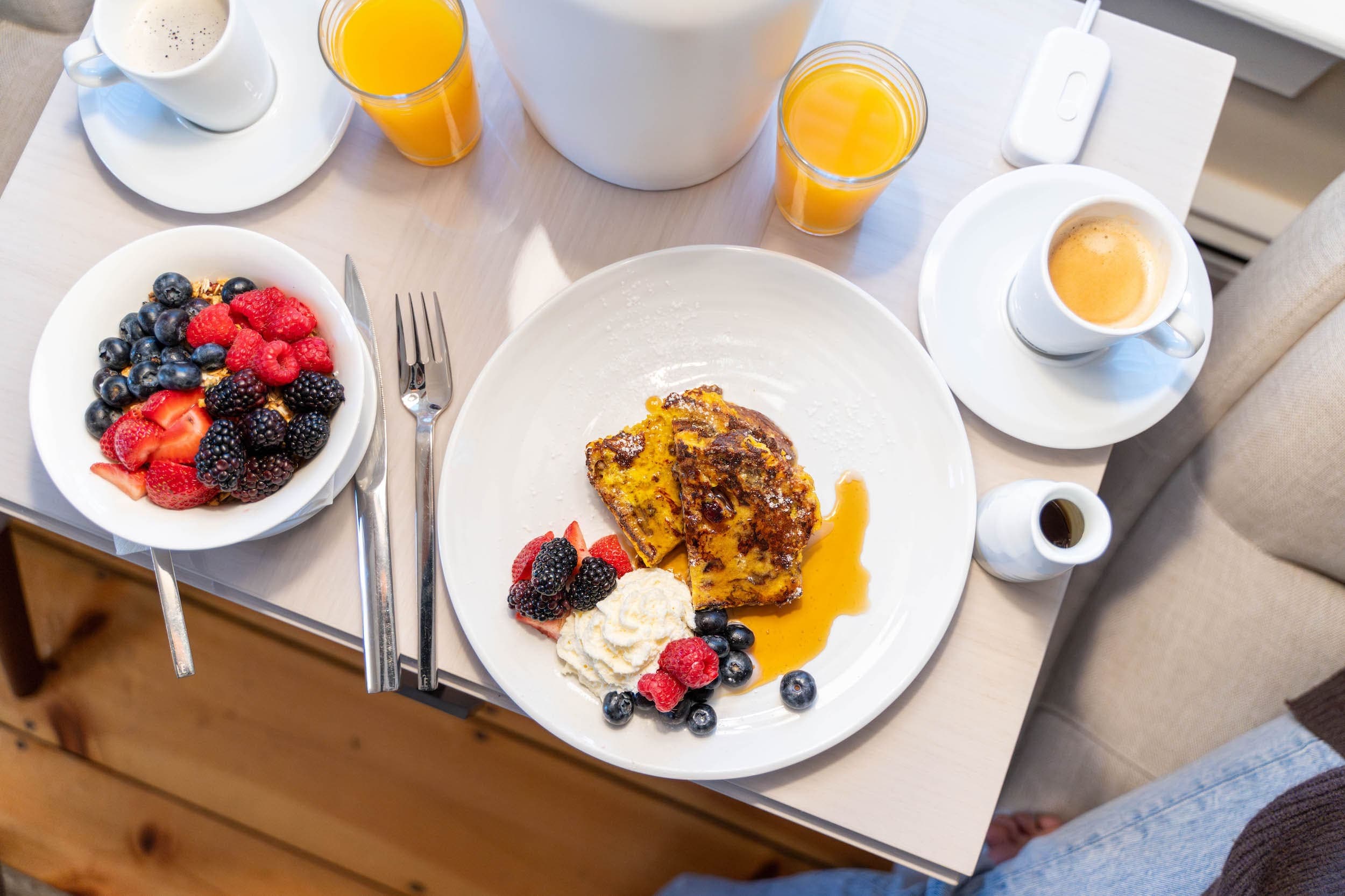An In-room breakfast of granola and berries, french toast , coffee , and juice