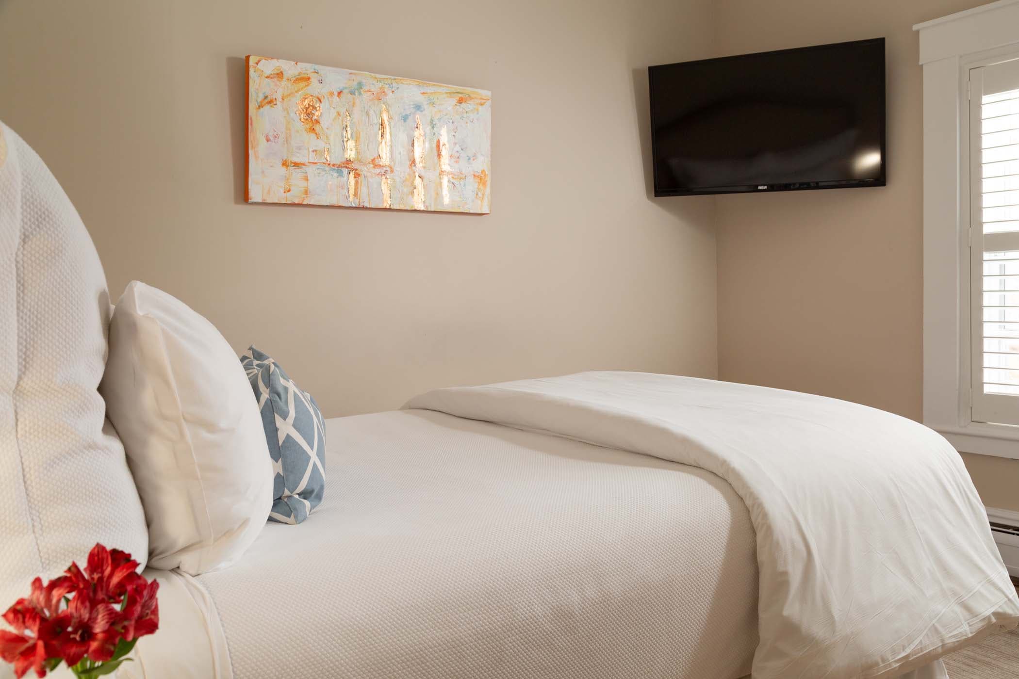 A queen bed and a TV mounted to the corner of the wall in Room 15 at Chatham Inn