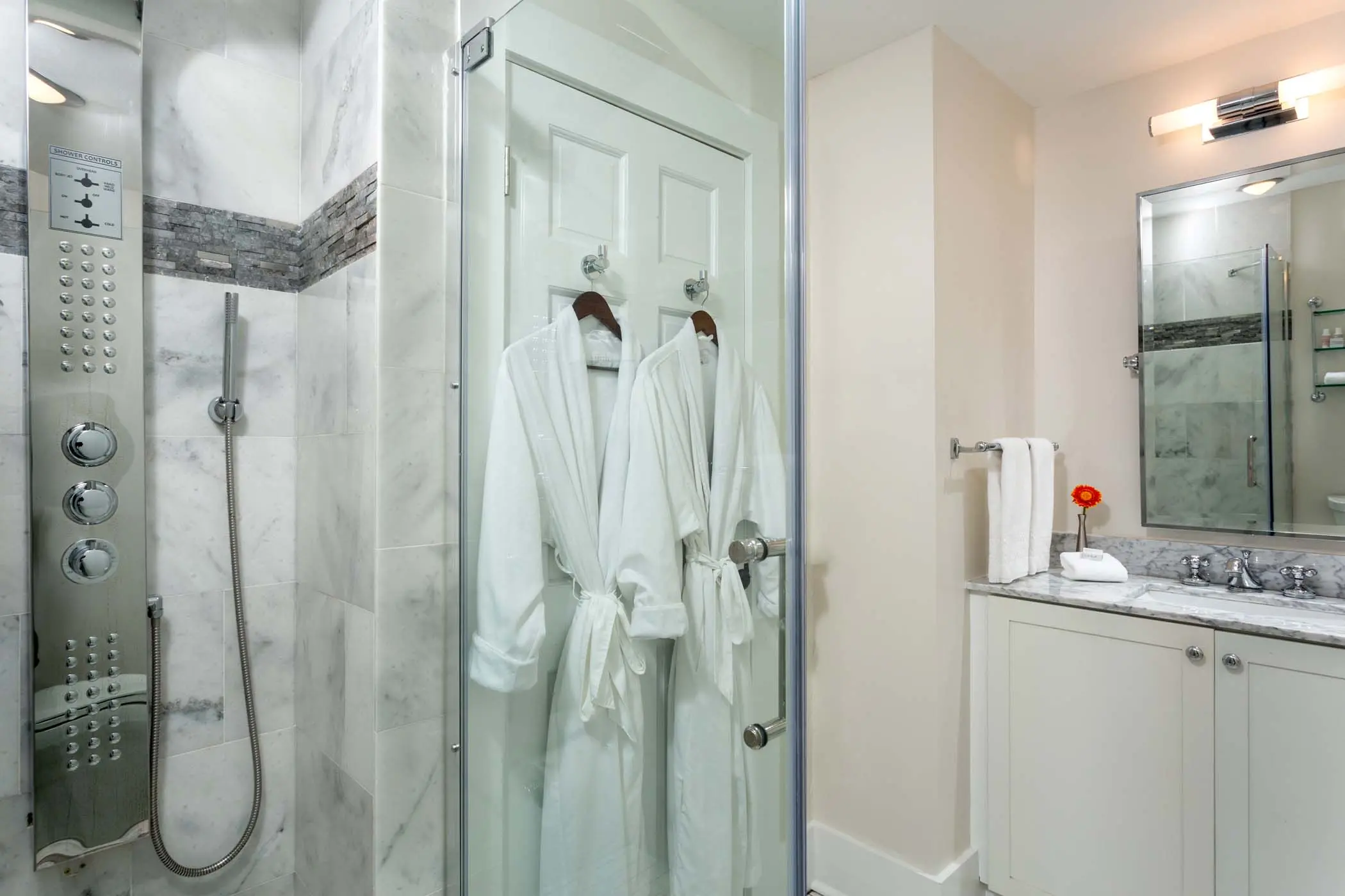 A spacious room 1 bathroom with a flower and 2 robes at Chatham Inn