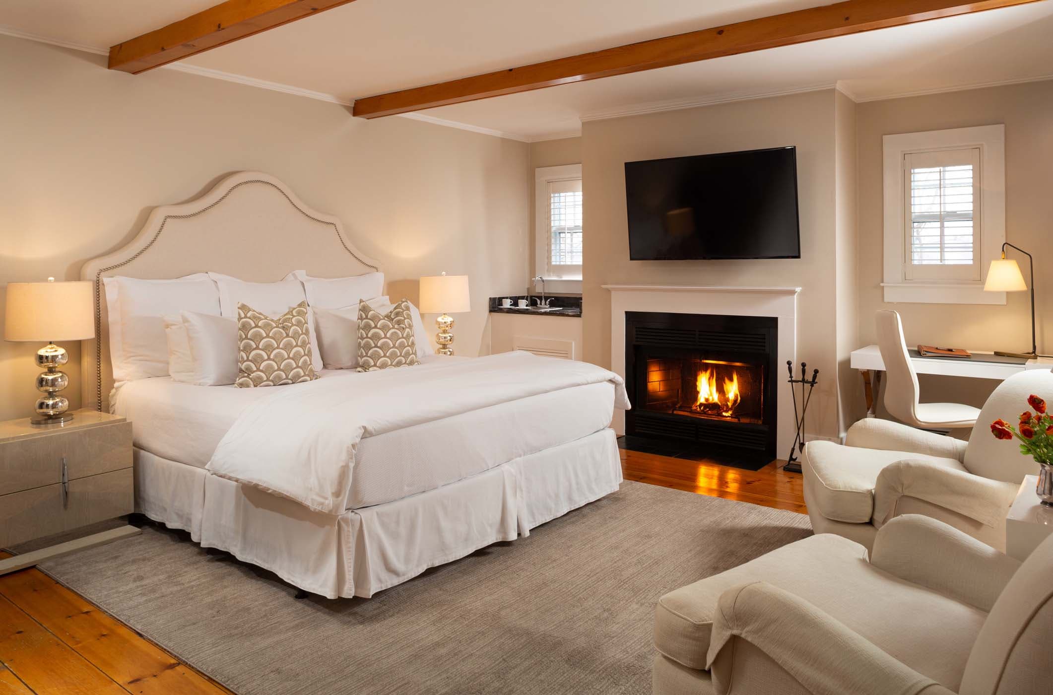 An elegant Room 2 in Chatham Inn with gorgeous wall art, fireplace and a cozy sitting area