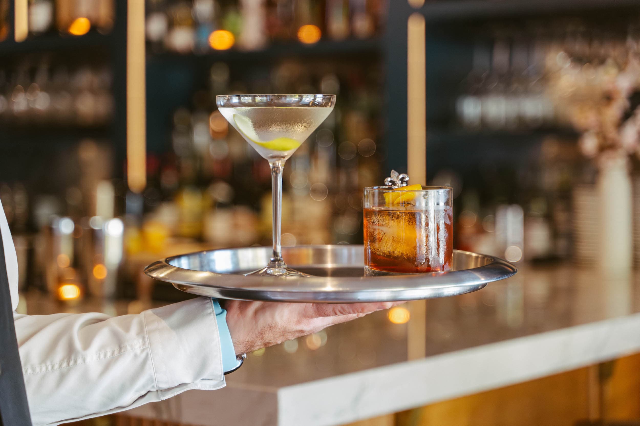 A server hand holding a tray of cocktails at Chatham