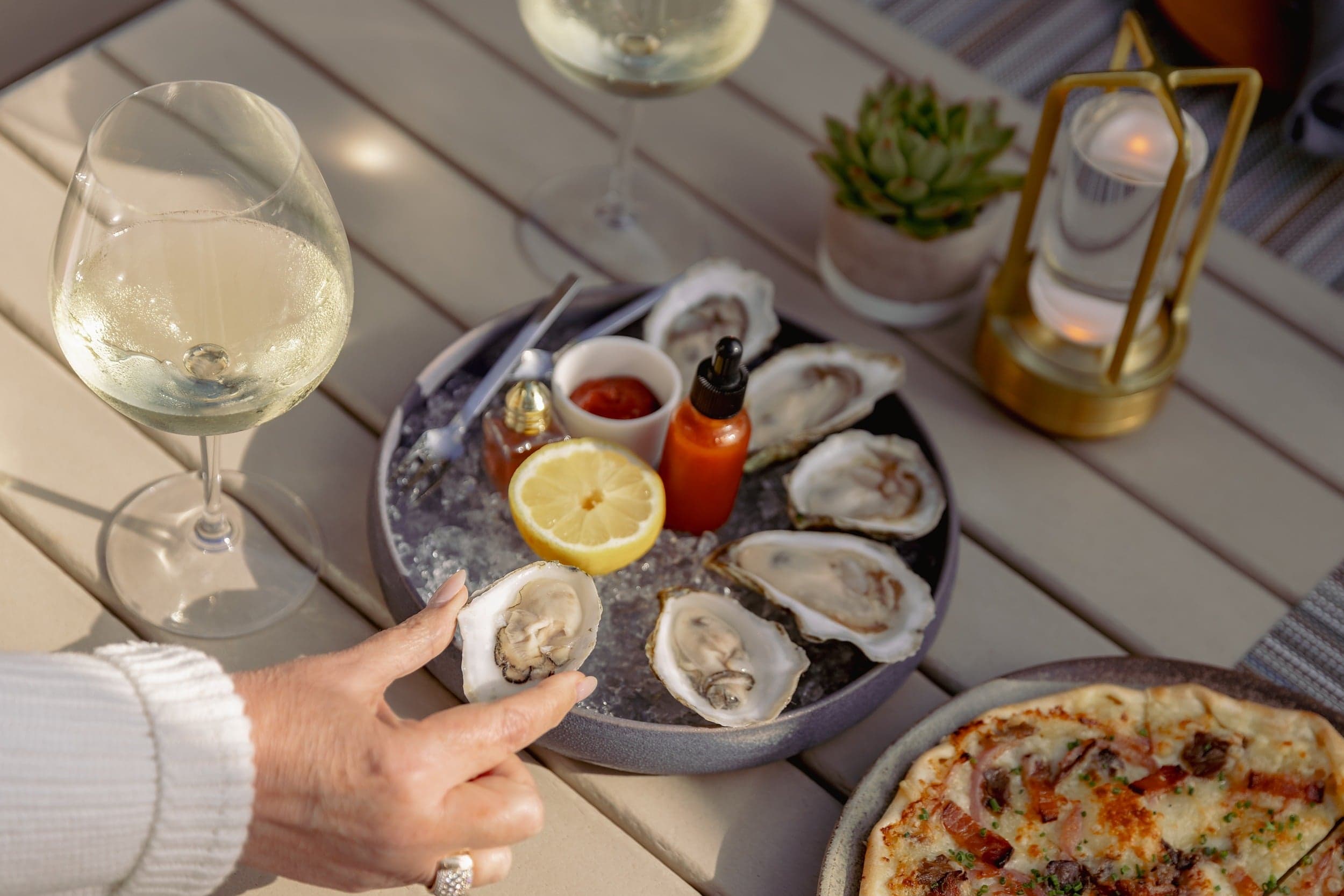 Fresh Cape Cod oysters on ice with lemon and chilled white wine on the sunny terrace at Chatham Inn, a Relais & Châteaux retreat in Chatham, Massachusetts.