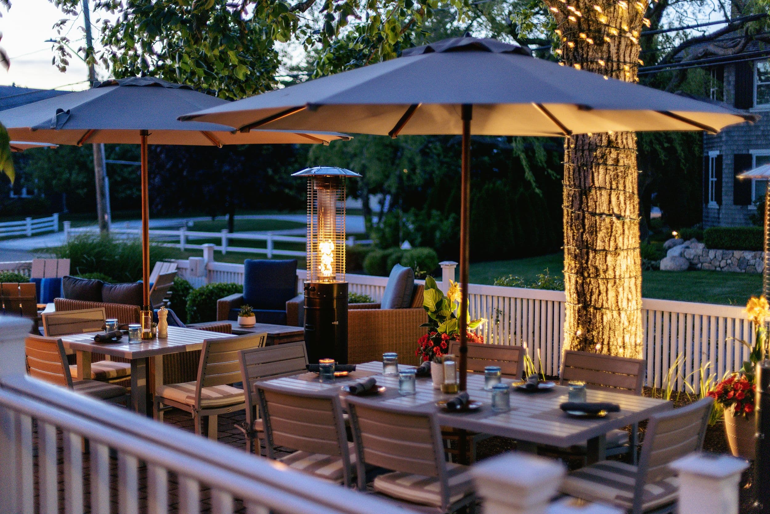 Candlelit outdoor patio dining under umbrellas at dusk at Chatham Inn, a Relais & Châteaux property in Chatham, Massachusetts.